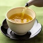 阿波晩茶を湯呑に注いている。山吹色のお茶のイメージ